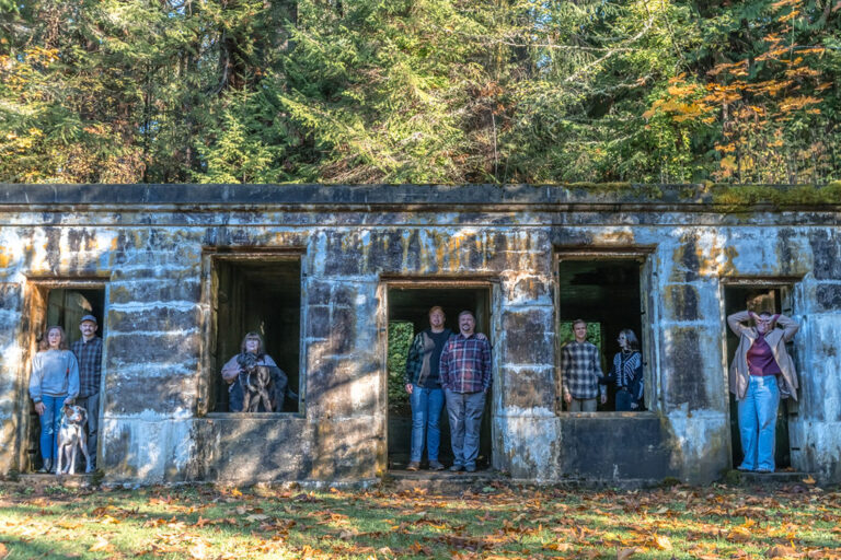 Extended family posing in the window openings of a historic stone structure in Western Washington