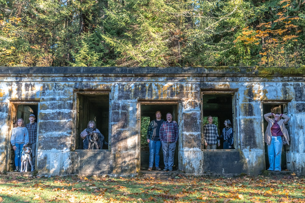 Extended family posing in the window openings of an old stone structure surrounded by fall color
