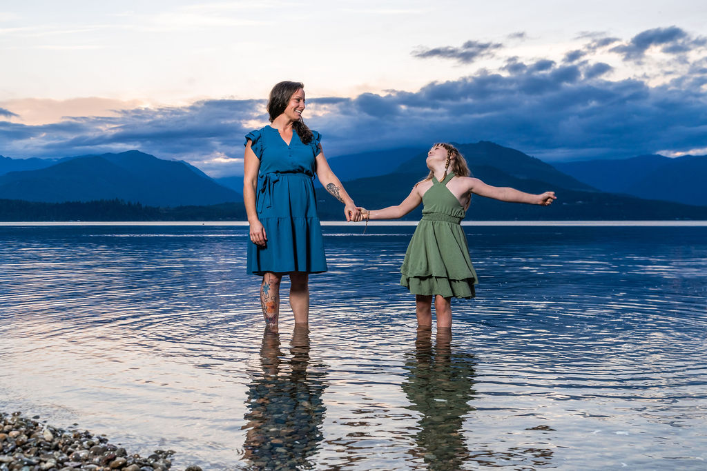 Mother and daughter holding hands in the shallow water at sunset during a family beach session in Washington