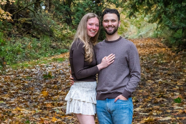Smiling couple embracing on a leaf covered path in the fall woods