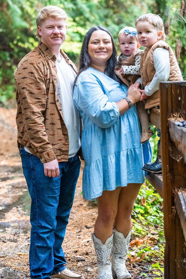 Young family of four posing by a rustic fence during an autumn family photo session in Kitsap County, Washington