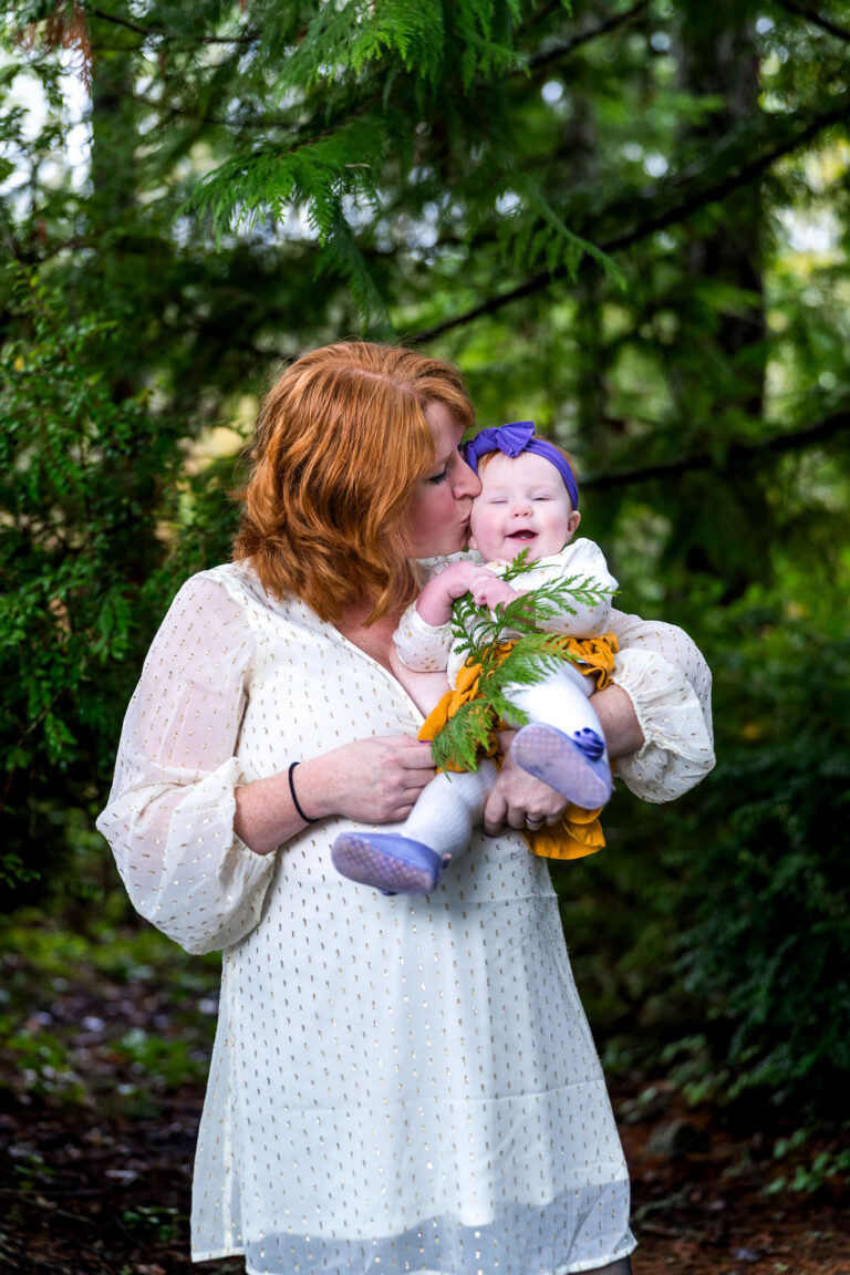 Mother kissing her daughter during an at home family session in Kitsap County
