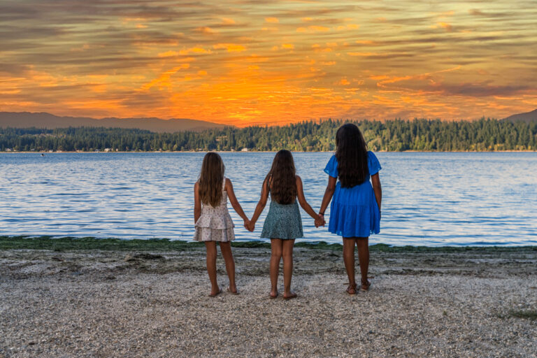 Three young sisters holding hands at sunset at Manchester State Park
