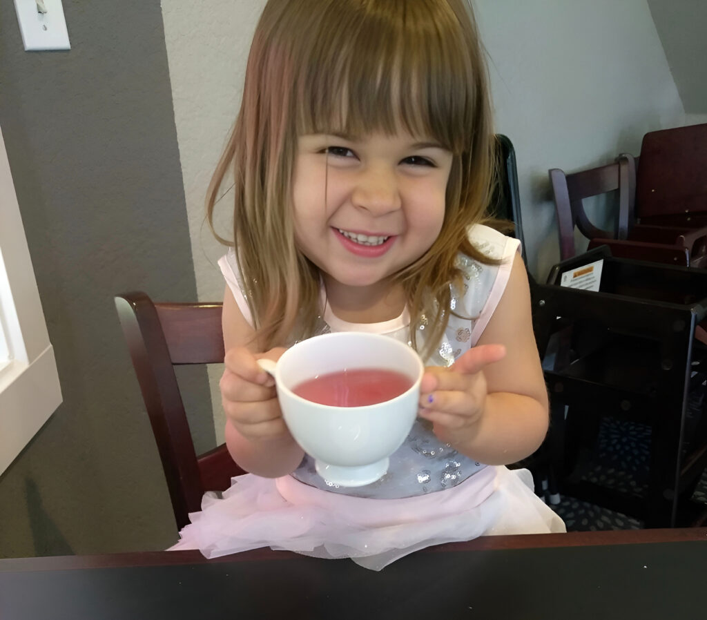 Ava my little girl with a tea cup smiling
