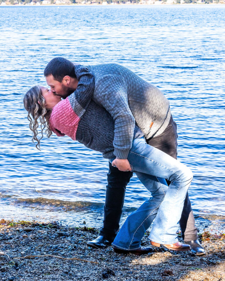 Newly engaged couple kissing on the beach at Manchester State Park during a Kitsap County engagement session