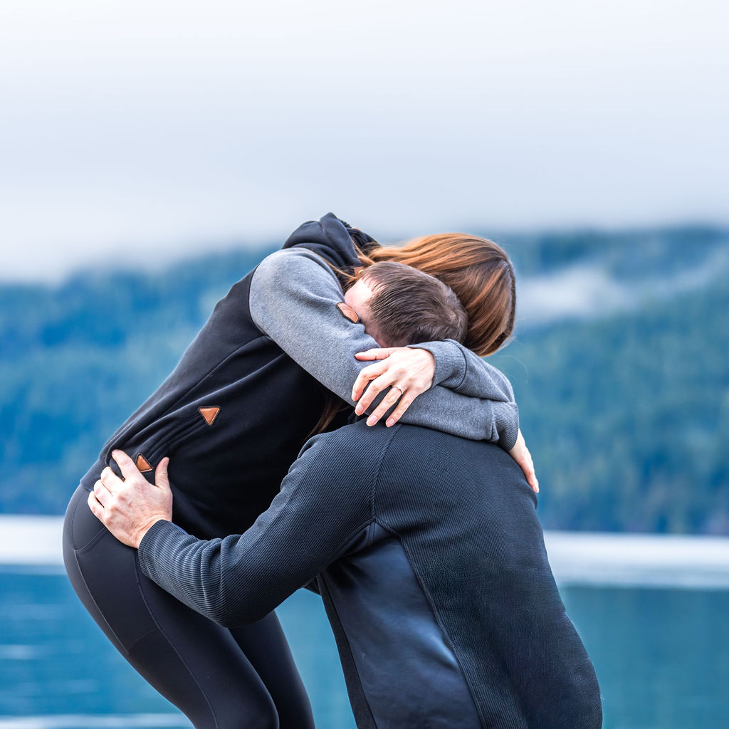 Engaged couple embracing on a dock during their engagement session at Lake Crescent in Olympic National Park.