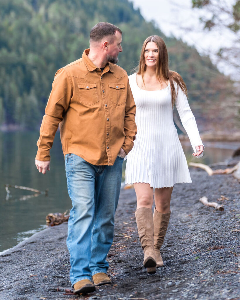 Engaged couple walking along the shoreline during their engagement session at Lake Crescent in Olympic National Park.