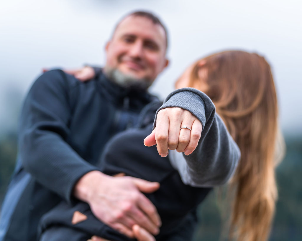 Newly engaged woman showing her engagement ring during a proposal photo session at Lake Crescent in Olympic National Park.