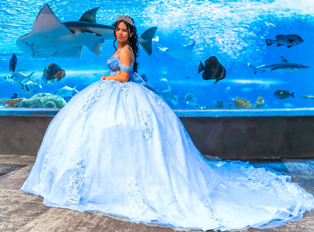 Quinceañera portrait in blue ball gown in front of shark tank at Seattle Aquarium