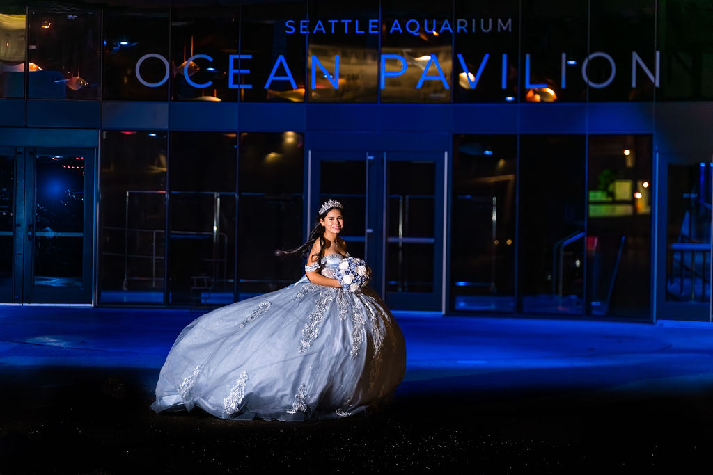 Quinceañera portrait in blue ball gown outside Seattle Aquarium Ocean Pavilion at night