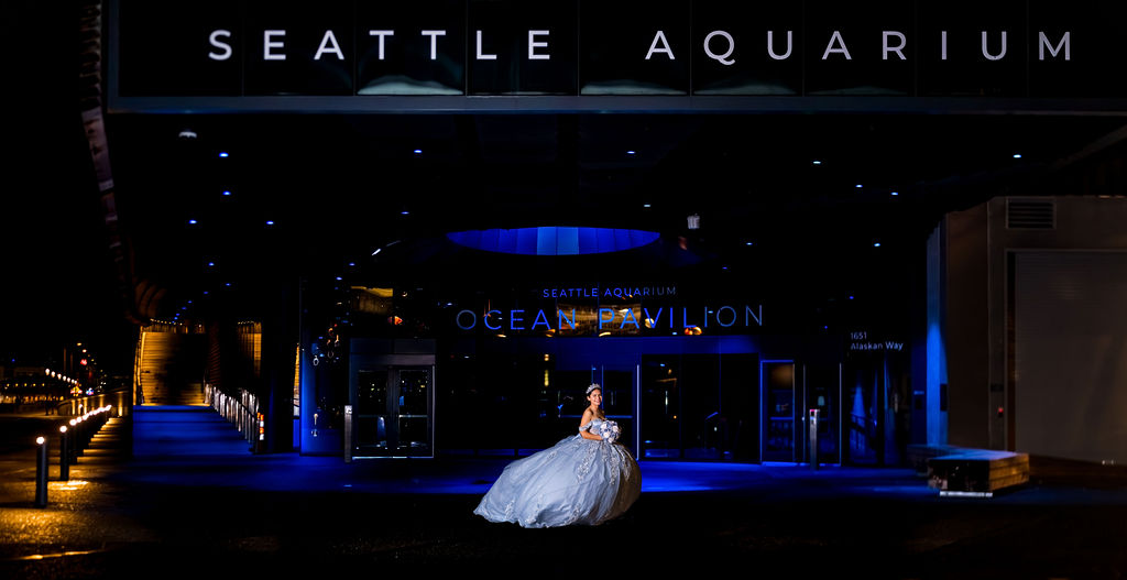 Quinceañera portrait in blue ball gown outside Seattle Aquarium Ocean Pavilion at night