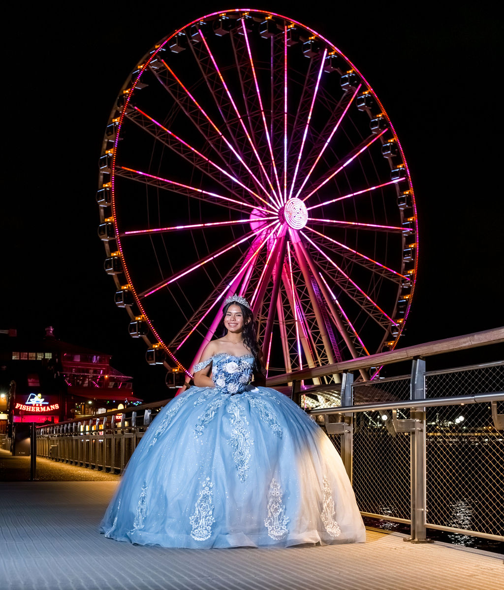 Quinceañera portrait in blue ball gown at Seattle Great Wheel on waterfront at night