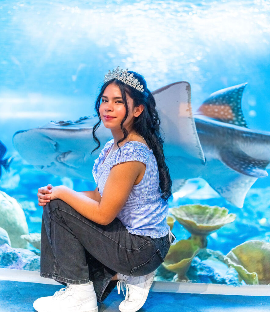 Quinceañera portrait with tiara in front of stingray exhibit at Seattle Aquarium