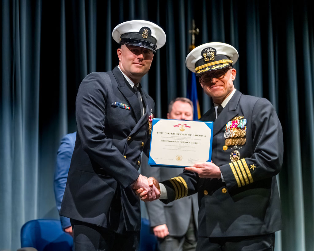 Master Chief with Officer holding award during retirement ceremony.