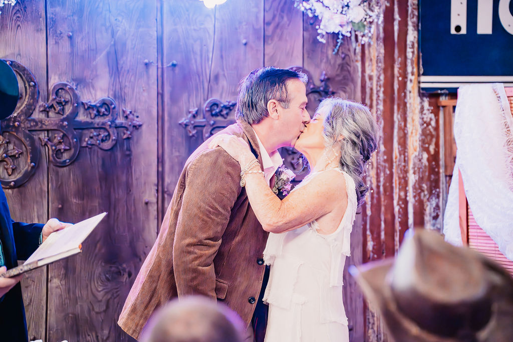 Bride and groom sharing their first kiss during their wedding ceremony at Burley Creek Nursery wedding venue in Port Orchard Washington