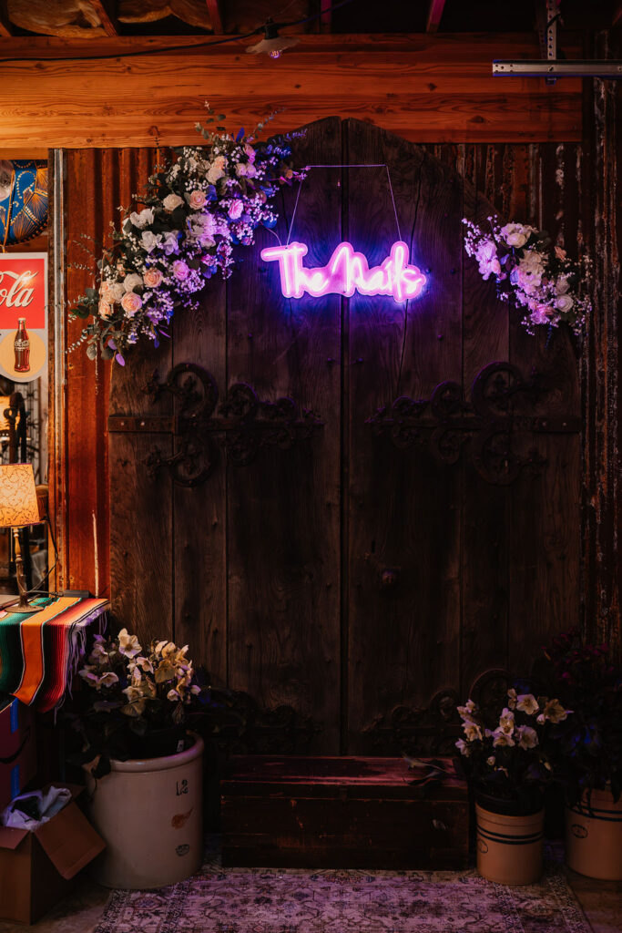 Wedding reception decor with neon sign and floral arrangement inside Burley Creek Nursery rustic barn venue in Port Orchard Washington