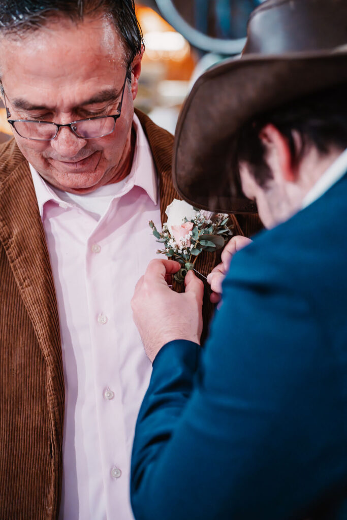 Groom having his boutonniere pinned before the ceremony at Burley Creek Nursery rustic wedding venue in Port Orchard Washington