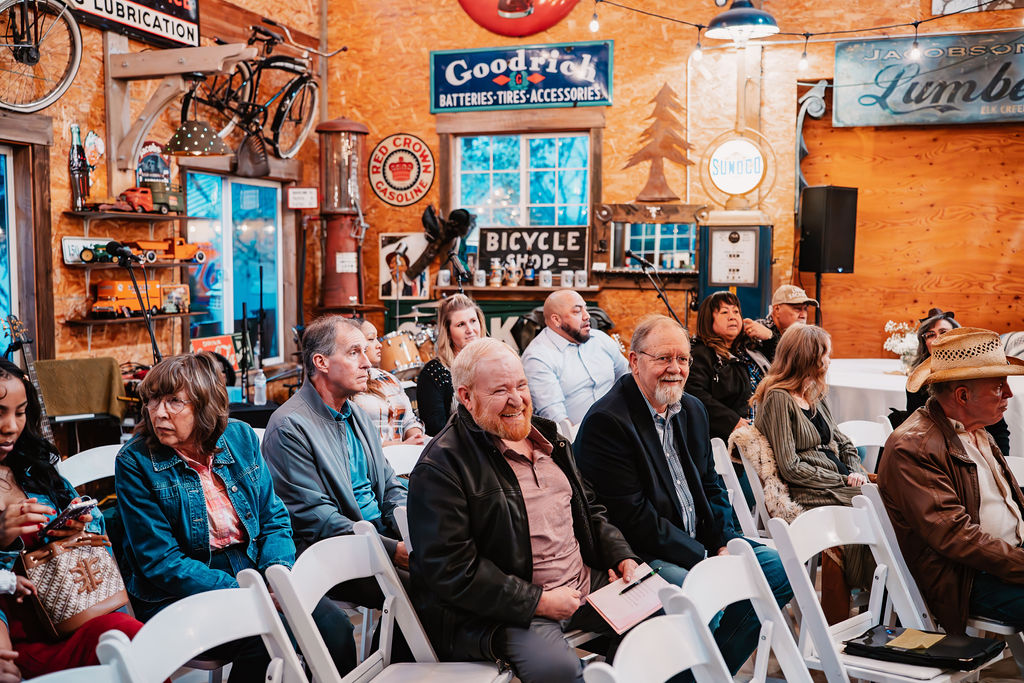 Wedding guests smiling and enjoying the ceremony inside the Burley Creek Nursery rustic wedding venue in Kitsap County Washington