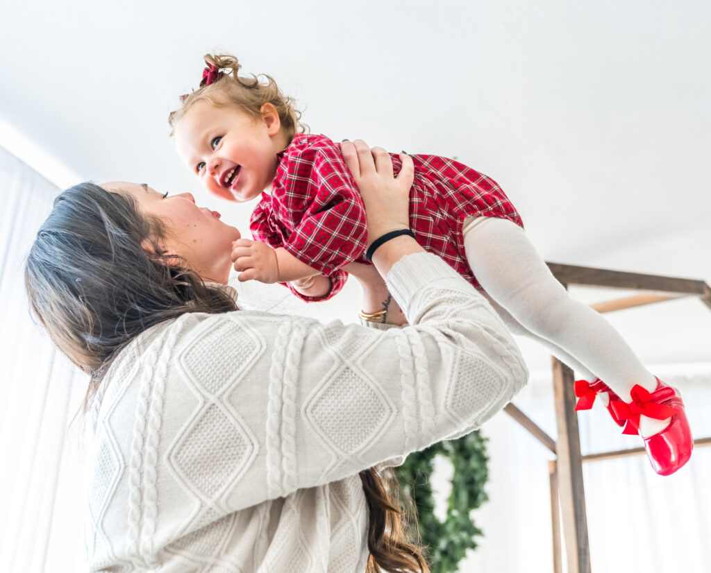 Mother lifting her laughing toddler during an indoor holiday family photo session in Washington