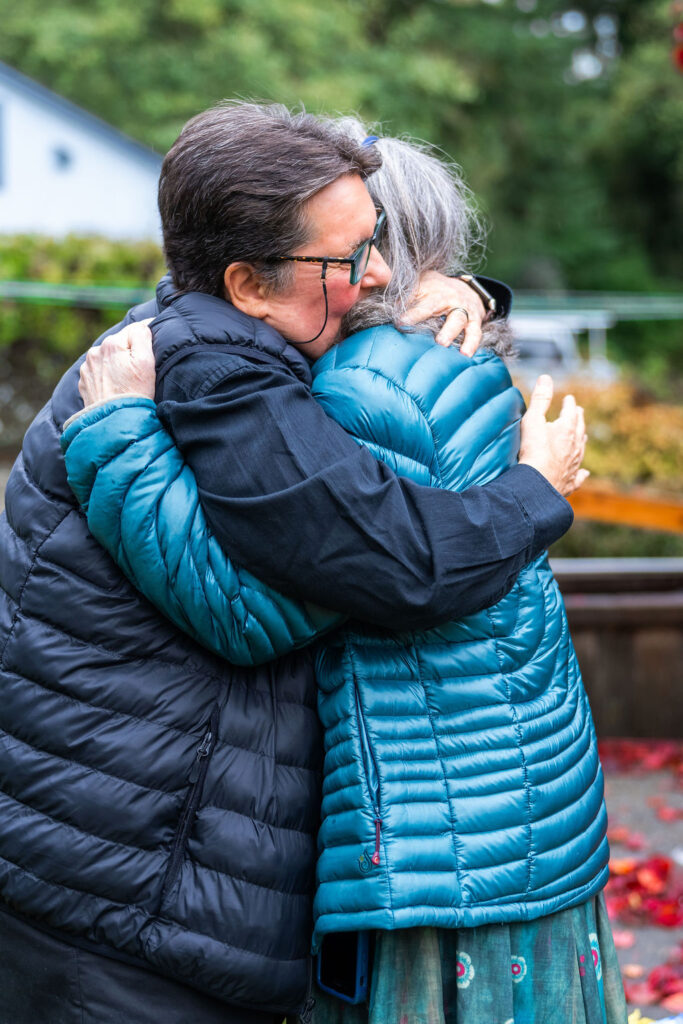 Two wedding guests embracing warmly during a fall wedding celebration on Vashon Island, Washington