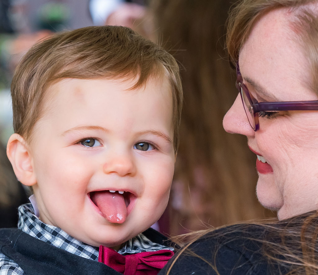 Young child with a bow tie smiling while being held by a guest during a Vashon Island wedding in Washington