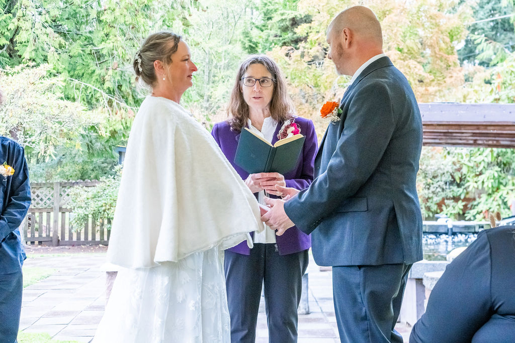 Bride and groom holding hands while exchanging vows with officiant during an outdoor wedding ceremony on Vashon Island, Washington