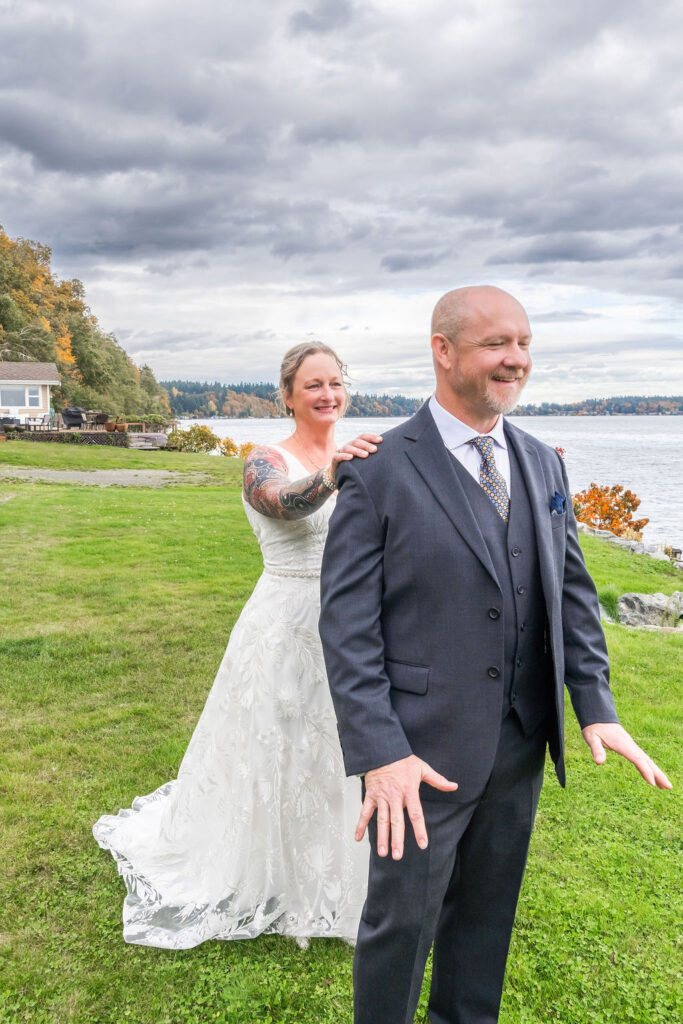 Bride tapping groom on the shoulder during their first look by the water at a Vashon Island wedding in Washington
