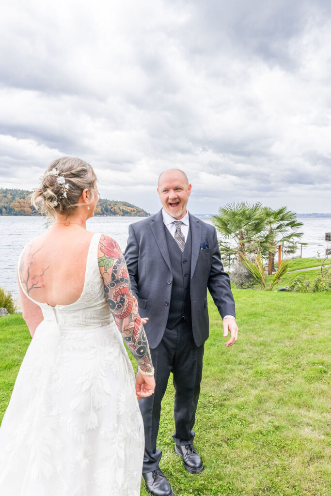 Groom reacting with excitement as he turns to see his bride during their first look at a waterfront wedding on Vashon Island, Washington