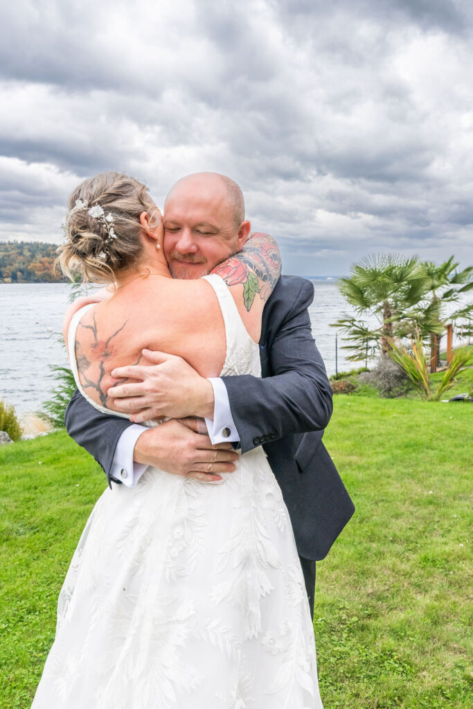 Bride and groom sharing an emotional hug during their first look at a waterfront wedding on Vashon Island, Washington