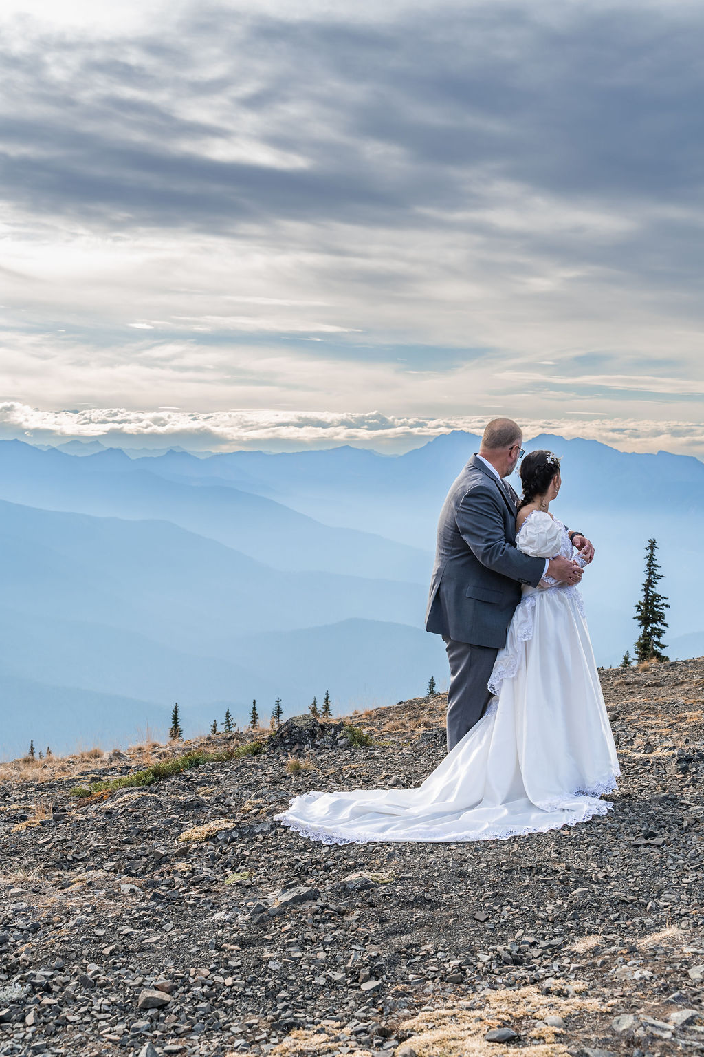Mountaintop wedding portrait of a couple above layered ridges in the Olympic Mountains near Port Angeles Washington
