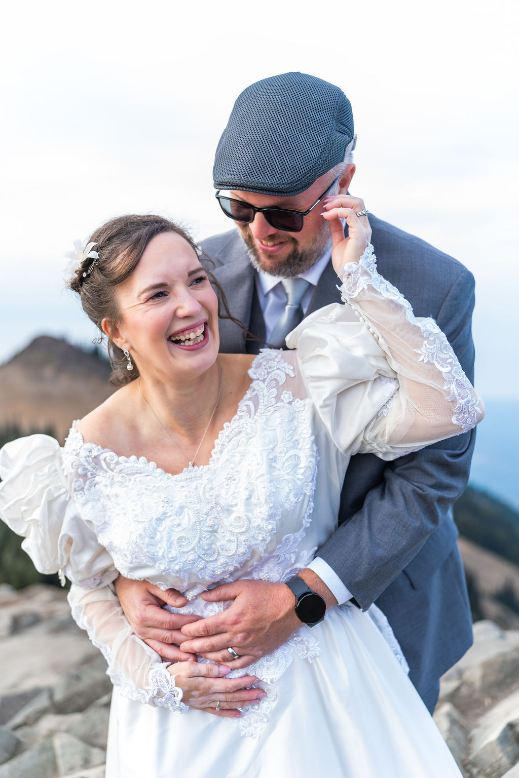 Couple in wedding attire laughing together during mountain portraits in Washington
