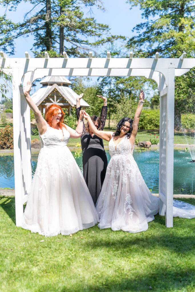Brides celebrating together by pond at Vickery Gardens outdoor wedding venue