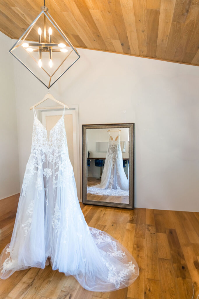Lace wedding dress hanging in bridal suite before ceremony at Vickery Gardens wedding venue