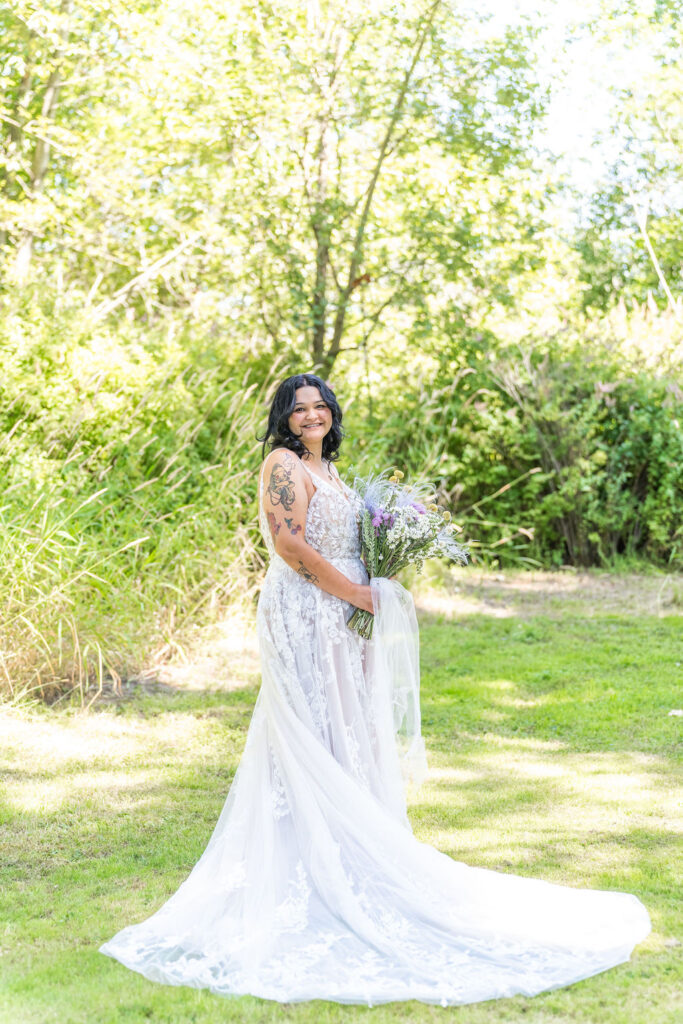 Bride holding bouquet and smiling in garden setting at Vickery Gardens wedding venue near Tacoma