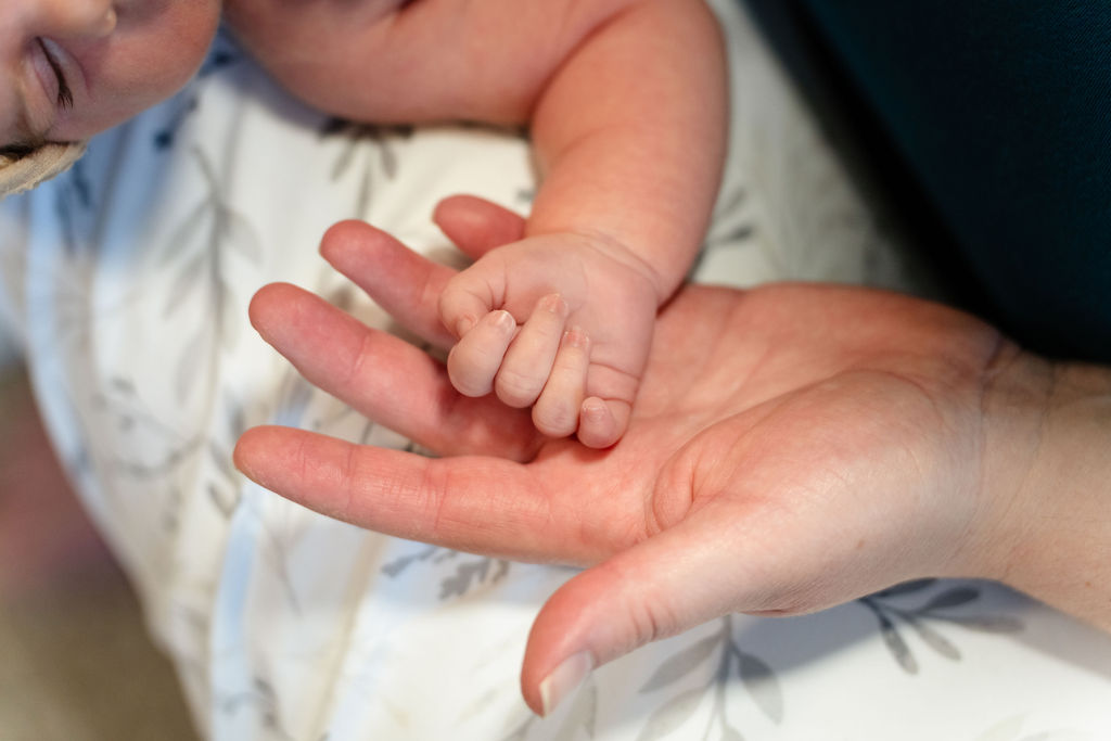 mom and newborn hand in hand.