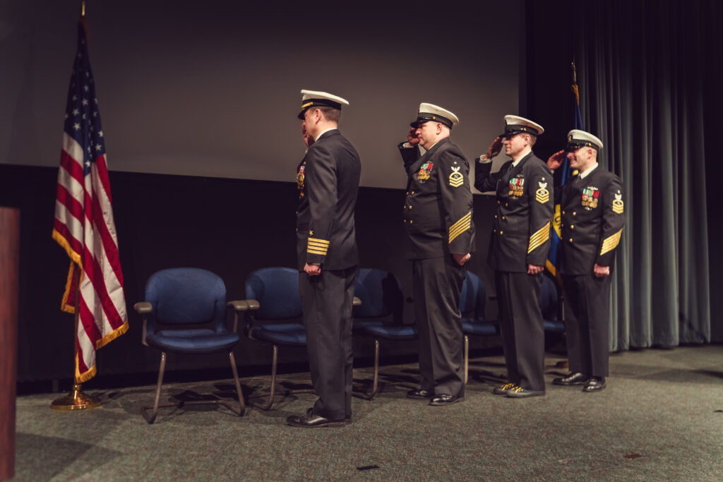Master chiefs saluting the American flag during ceremony