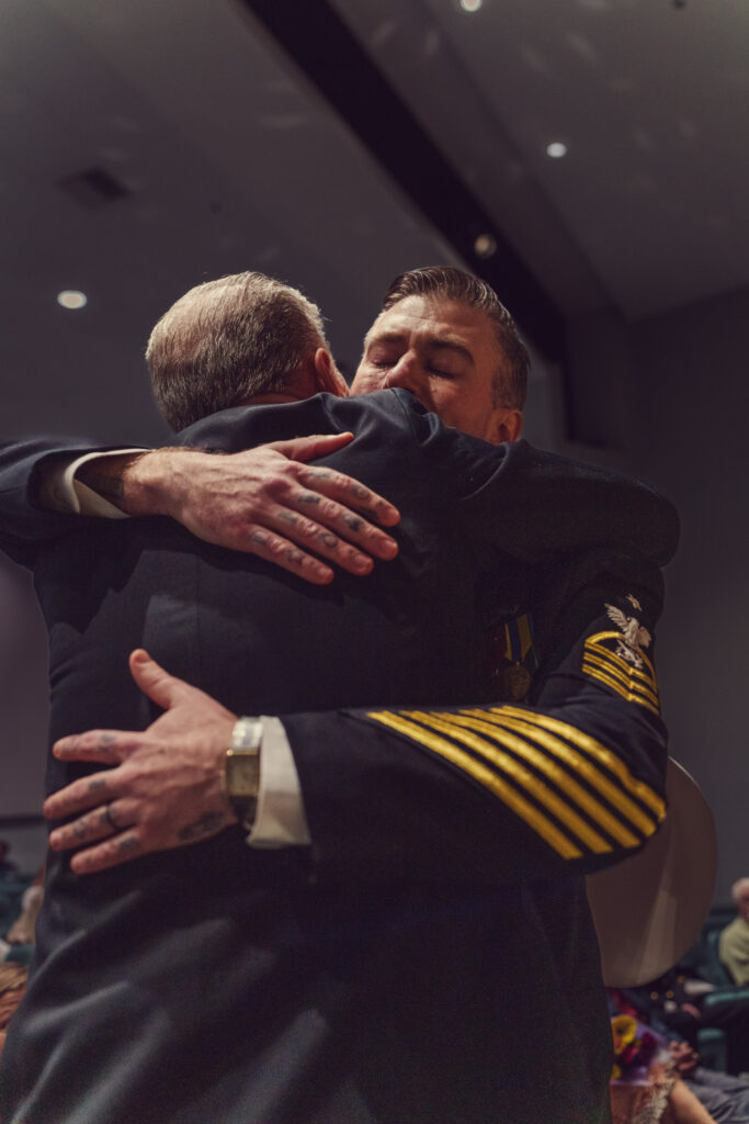 Emotional moment between father and soon during ceremony where they are hugging.
