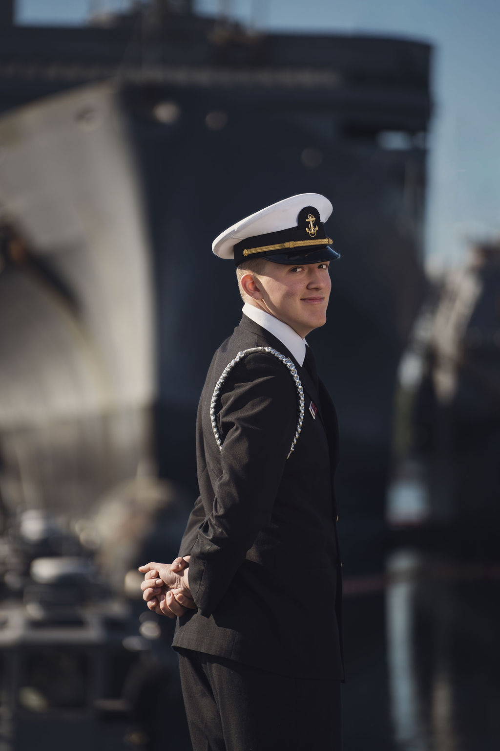 Senior looking back with navy ships in background.