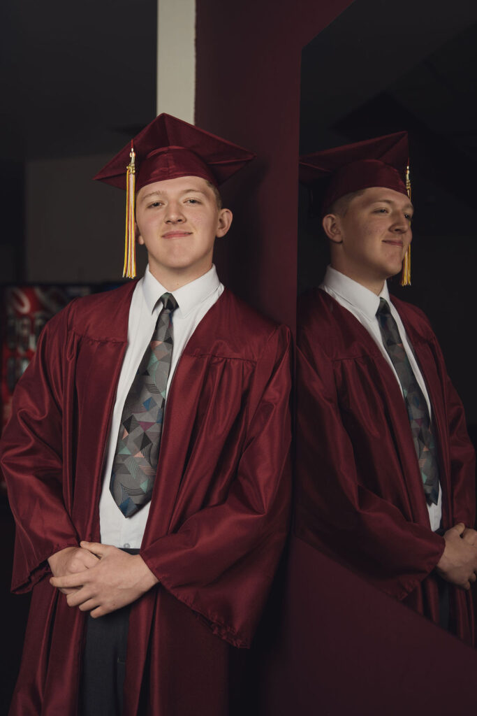 Zach showing off cap and gown with a reflection.