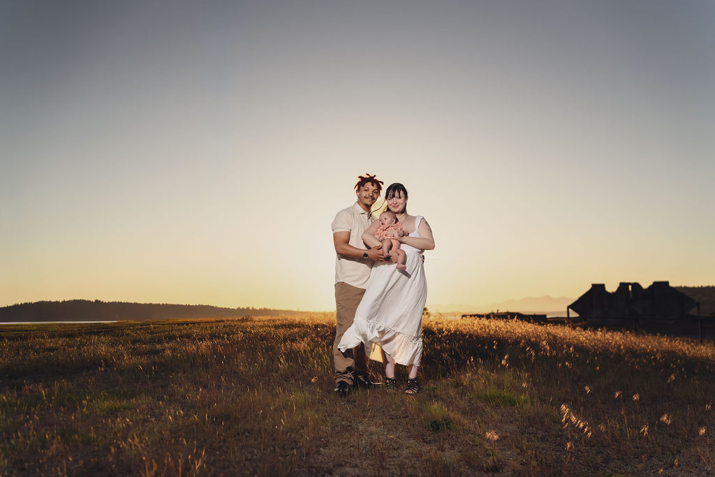 Leia and Ivory holding Jessica with sunset in golden tones at chambers bay tacoma