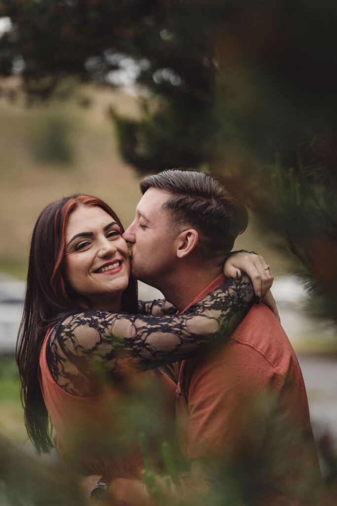 Madison and John Portrait at Chambers bay in Tacoma Washington Maddison looking at the camera and Jon Kissing her