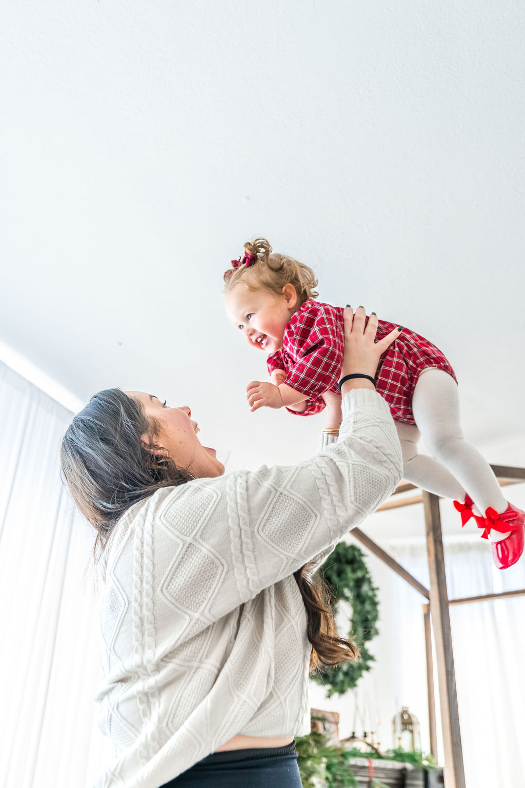 Family photographer capturing a mother lifting her laughing toddler overhead during an indoor family studio session in Washington