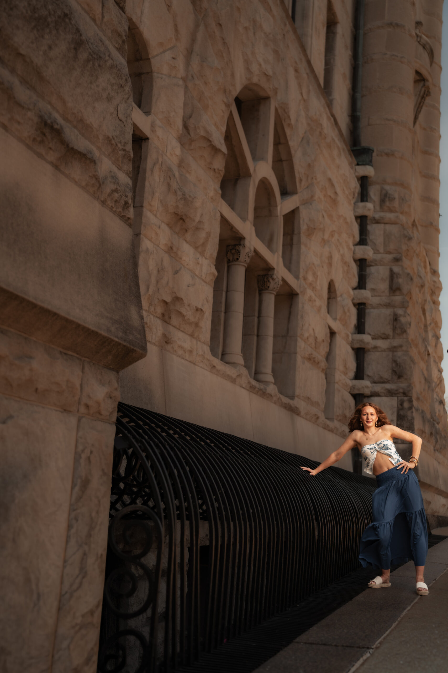 Senior portrait of a young woman leaning on an ornate iron railing