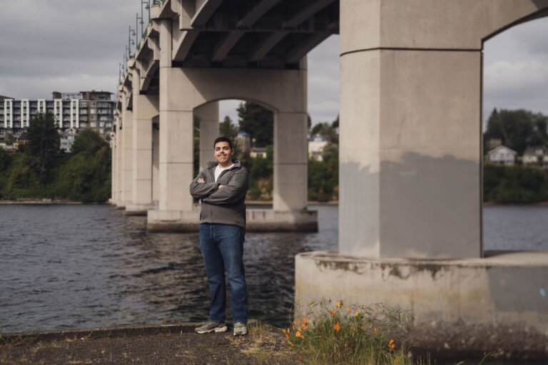 Kitsap County senior photographer portrait of a high school senior standing under a bridge beside the water