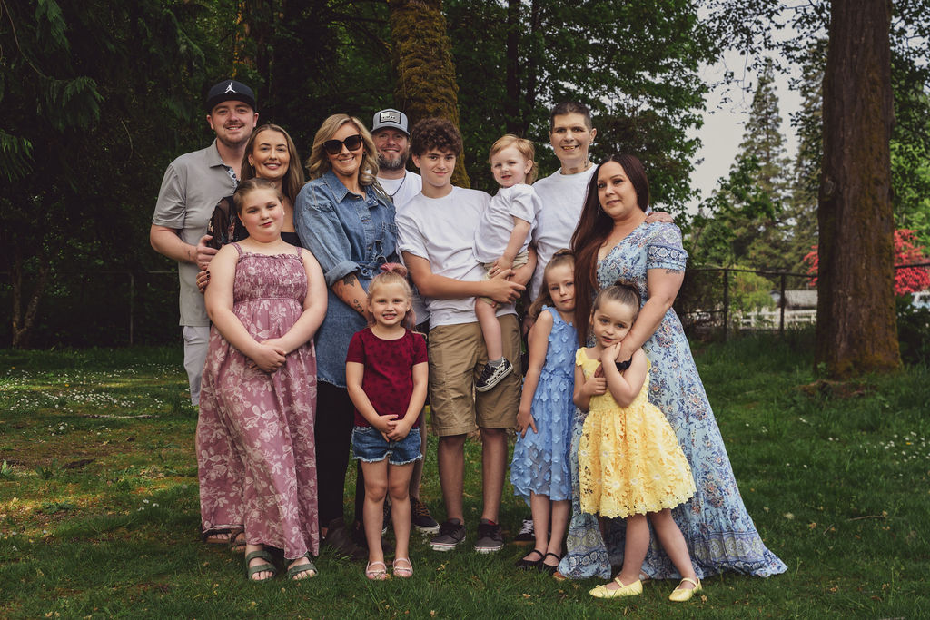Large extended family with children gathered together among the trees at a green Kitsap County park