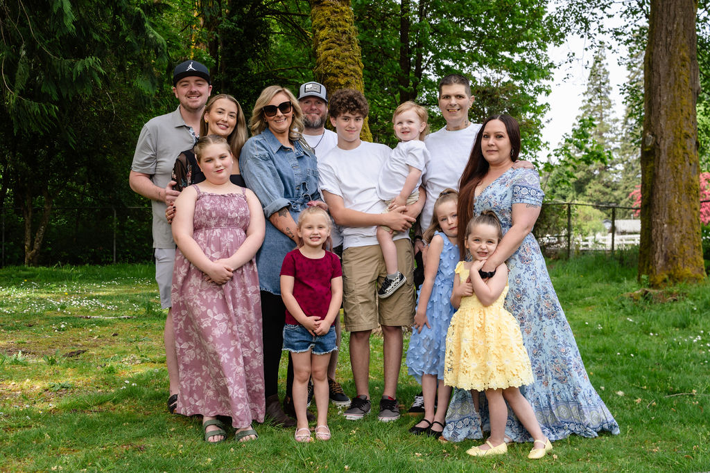 Large extended family posing together with their children among the trees at a Kitsap County park