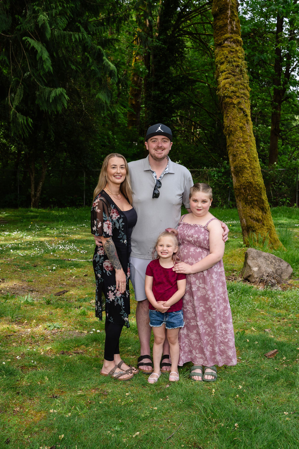 Family of four posing under the trees at a Kitsap County park