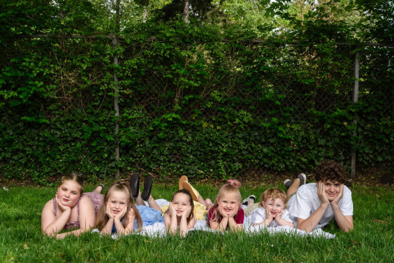 Kitsap County cousins lying in a row in the grass during an extended family park session