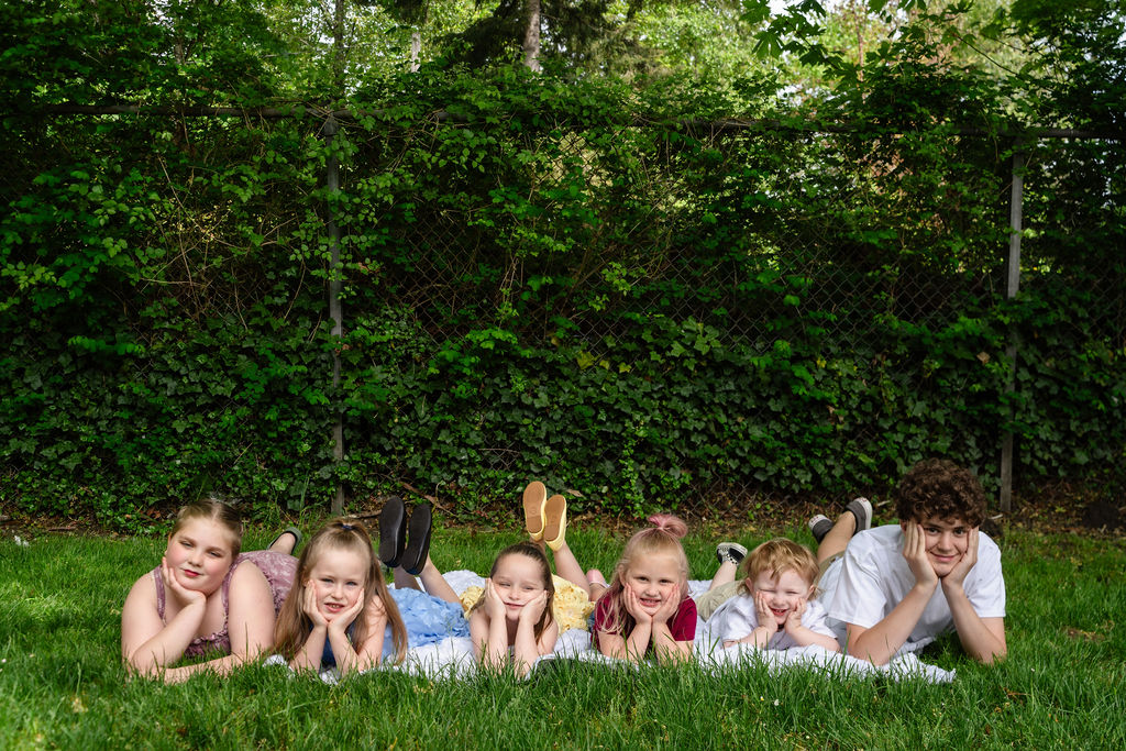 Group of children lying together in the grass during an outdoor family photo session in Washington