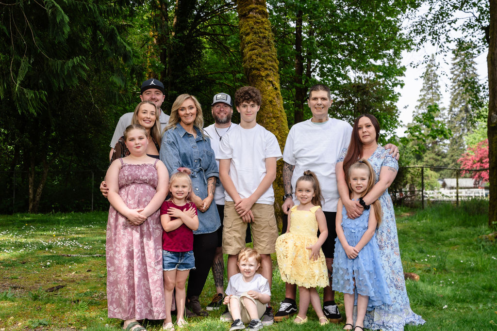 Large extended family gathered together under a mossy tree at a green Kitsap County park